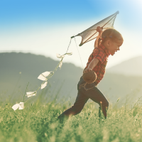 Kind mit Drachen läuft über ein Feld