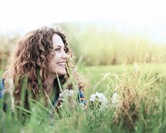 Frau liegt in der Wiese und schaut nach rechts