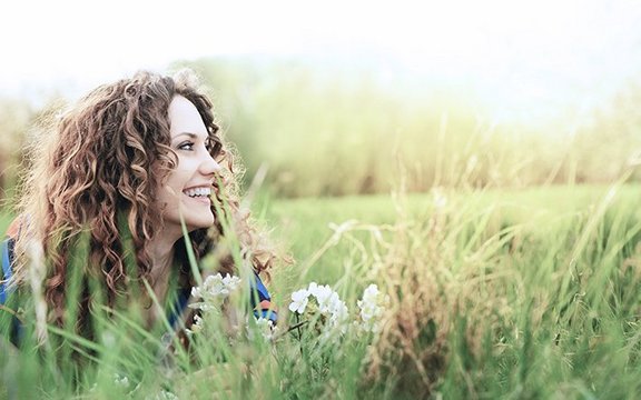 Frau liegt in der Wiese und schaut nach rechts