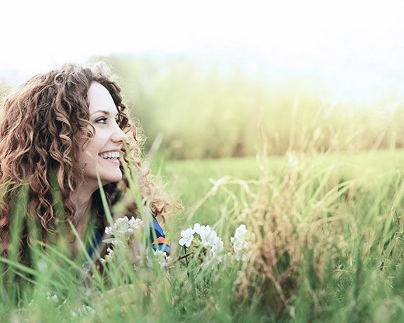 Frau liegt in der Wiese und schaut nach rechts