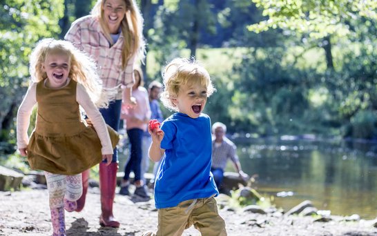 spielende Kinder mit Frau am Wasser