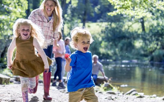 spielende Kinder mit Frau am Wasser