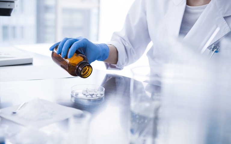 Labor Frau schüttet Tabletten in eine Petrischale