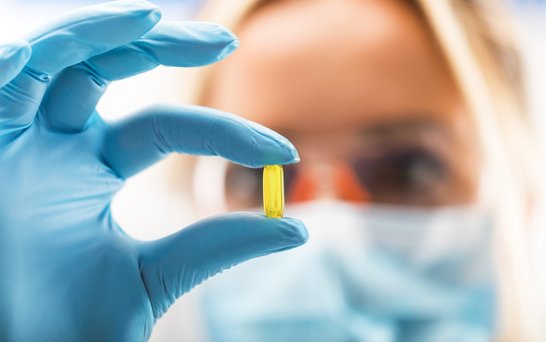 gelbe Pille in den Händen von Chemielaborantin