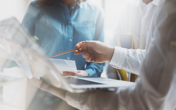 ein Person zeigt mit dem Stift auf ein Mac-Book