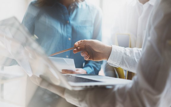 ein Person zeigt mit dem Stift auf ein Mac-Book