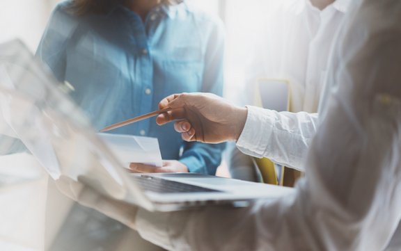 ein Person zeigt mit dem Stift auf ein Mac-Book