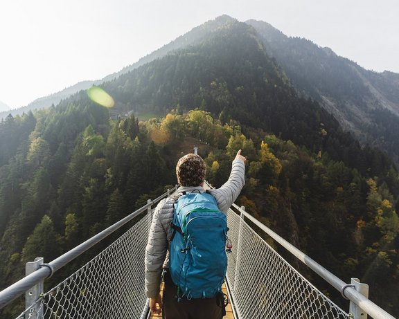 Mann auf Berg, zeigt in die Berge