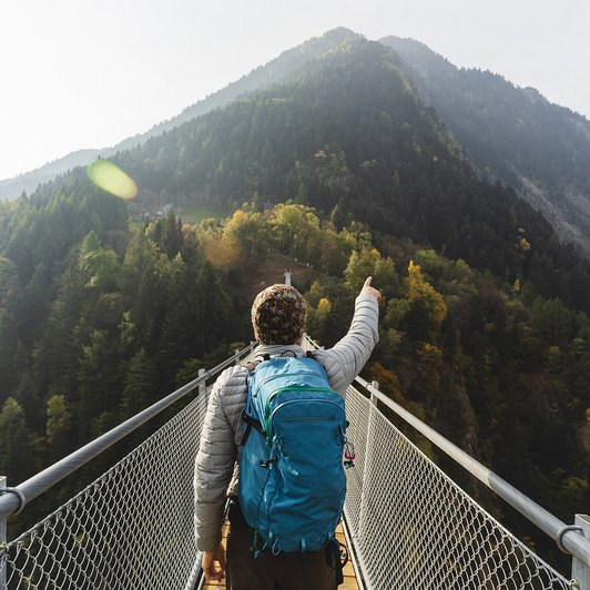 Mann auf Berg, zeigt in die Berge