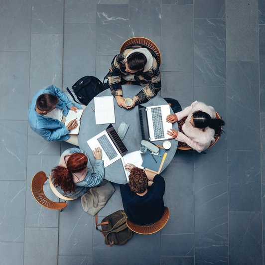 Personen am Tisch mit Laptops