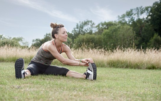 Frau in Sportklamotten beim Dehnen